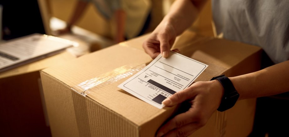 Close-up of deliverer attaching data label on cardboard box in t